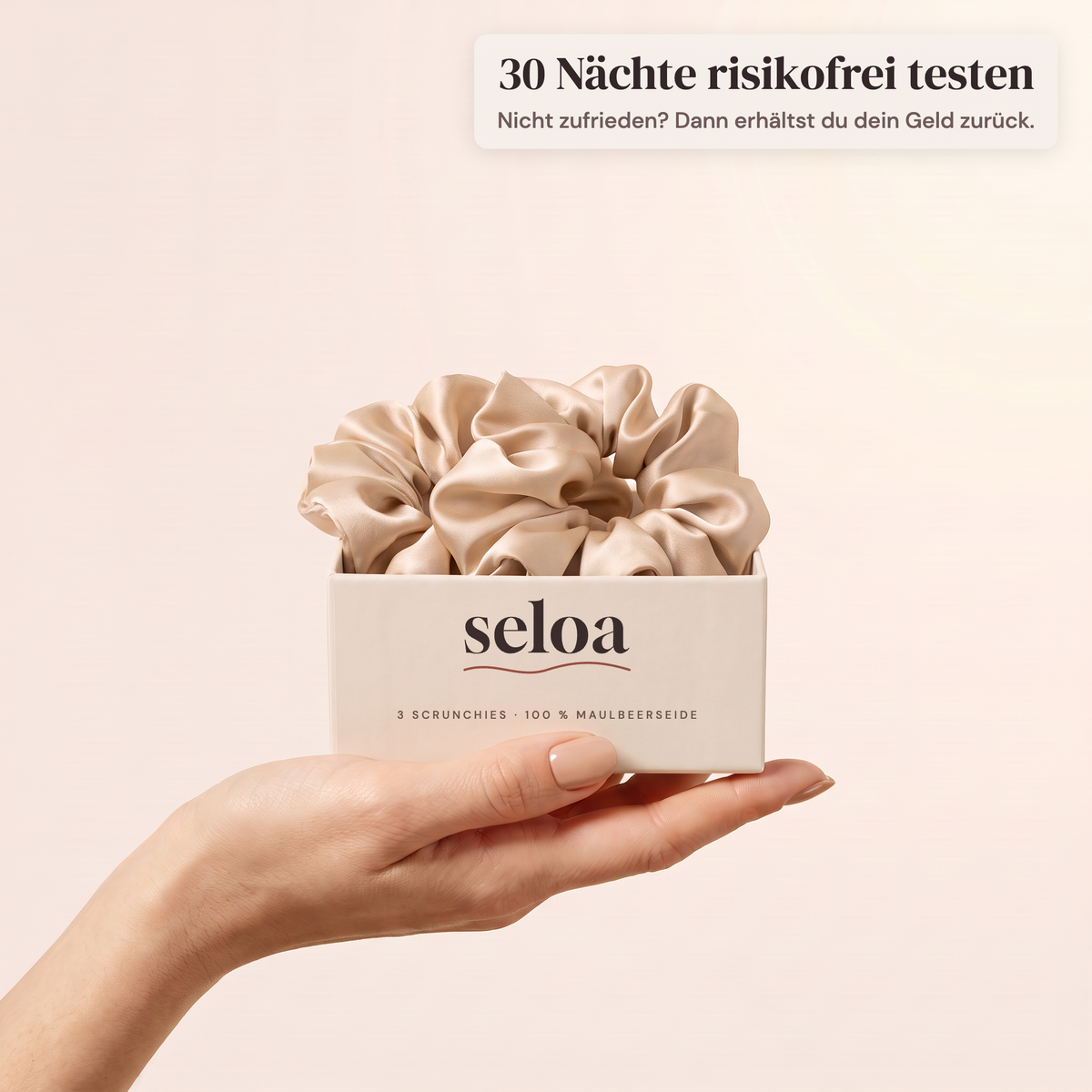 Hand hält die Seloa Box mit drei Seiden-Scrunchies in Champagner – 30 Nächte risikofrei testen